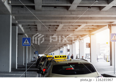Taxi car Queue yellow taxi symbol  on roof stand waiting at parking of airport terminal or railway station Under Concrete Structure Transportation Hub. Urban street transportation comfort service 116285967