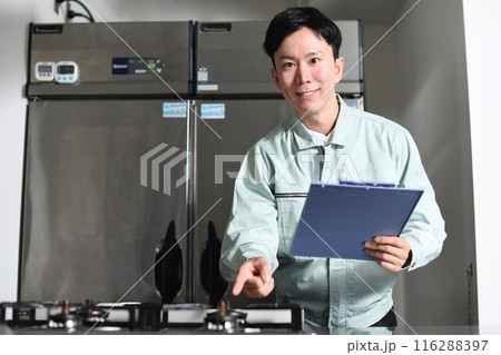 厨房を点検する作業服を着たアジア人男性 116288397