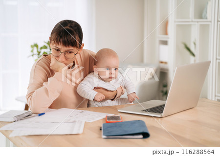 Single mother trying to solve family financial problems while taking care of her baby Single mother trying to solve family financial problems while taking care of her baby 116288564