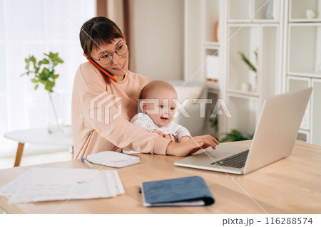 Business mom working remotely on laptop while taking care of her baby 116288574