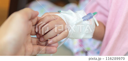 Mother holding child hand with saline IV solution in hospital 116289970