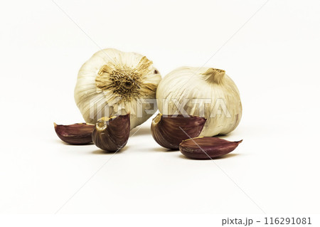 Two heads and cloves of garlic on a white background. On a white background lie heads and raw garlic cloves Two heads and cloves of garlic on a white background. On a white background lie heads and raw garlic cloves 116291081