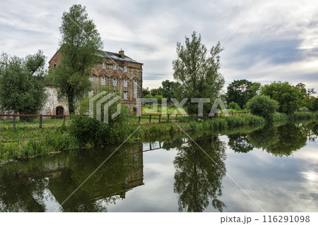 The old abandoned brick building is reflected in the surface of the reservoir. On the river bank is an abandoned old brick building and is reflected in the surface of the water 116291098