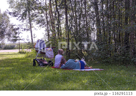 In the shade of trees in the fresh air resting family with a stroller 116291113