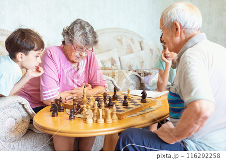 Grandparents playing chess with their grandchildren Grandparents playing chess with their grandchildren 116292258