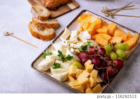 Cheese plate with different cheese, grapes and melon. 116292513