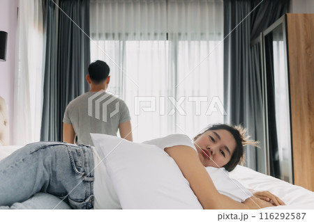 Wife is sulking on the bed and husband turn his back. 116292587