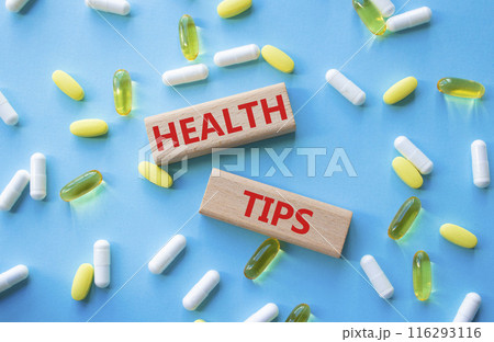 Health Tips symbol. Wooden blocks with words Health Tips. Beautiful blue background with pills. Medicine and Health Tips concept. Copy space. 116293116