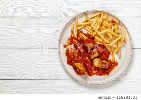 pork sausages in a curry sauce with french fries 116293333