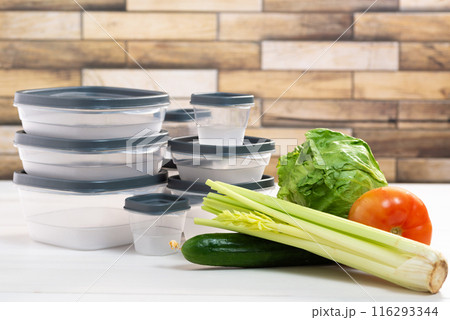 A stack of plastic containers and raw vegetables on the table. Storage for vegetables and fruits in plastic containers 116293344
