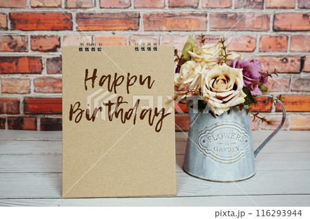 Happy Birthday text message and artificial roses flowers in metal vase decoration on wooden background Happy Birthday text message and artificial roses flowers in metal vase decoration on wooden background 116293944