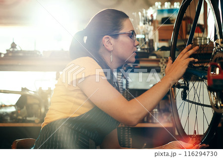 Bicycle technician, working and repair in shop with frame, chain and tools for maintenance or cycling. Woman, bike and mechanic in workshop as handyman for gear, inspection and safety with glasses 116294730