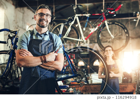Man, portrait and arms crossed at work in bicycle repair shop or maintenance garage. Bike, mechanic and service with a professional handyman for startup, small business and workshop for fixing Man, portrait and arms crossed at work in bicycle repair shop or maintenance garage. Bike, mechanic and service with a professional handyman for startup, small business and workshop for fixing 116294918