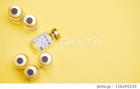 Medical, Covid vaccine and bottle in studio, innovation in health care for pandemic. Yellow background, glass container and medicine with research for virus, chemistry development for human wellness 116295230