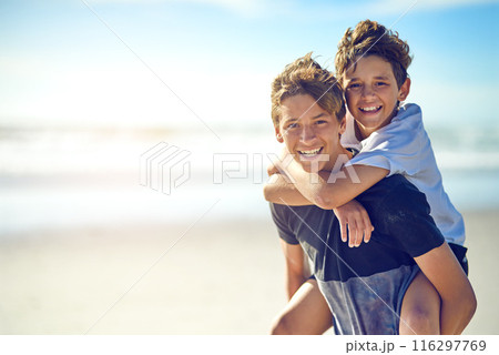 Piggyback, portrait or boys at ocean with smile or love for fun summer vacation, holiday or playing. Siblings, mockup space or happy kids outdoors in Spain at beach or sea for travel or family memory 116297769