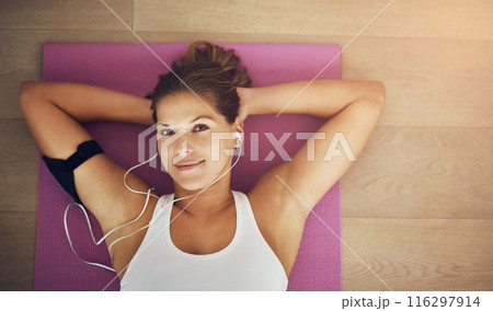 Woman, relax and listening to music on yoga mat with portrait for health, wellness and exercise. Happy face of young person with audio streaming of workout podcast with break or rest on floor above 116297914