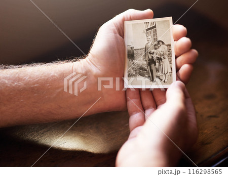 Hands, holding and vintage photograph in closeup of parents for memories or reflection in house. Nostalgia, person and love with pain for death with emotional support, gratitude and care for family. 116298565