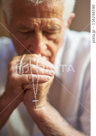 Cross, rosary and senior man with prayer at home for spiritual healing, faith or hope in religion. Christian, retirement and elderly person with praying for peace, blessing or guidance by Holy Spirit 116298590