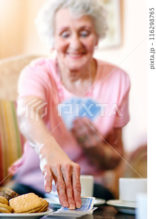 Elderly woman, table and hand with playing cards in retirement home for fun, activity and strategy. Happy, senior person and relax with snack in game for competition, contest and problem solving 116298765