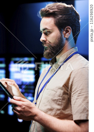 Cloud computing business executive imputing audit data in server room supporting AI through high performance computing. Skillful expert making sure supercomputers are operating flawlessly 116298920