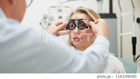 Doctor, ophthalmologist and woman with test frame for eye health, consultation and exam in clinic. Optometry, trail and patient on lens for vision check, wellness and glasses for eyesight correction Doctor, ophthalmologist and woman with test frame for eye health, consultation and exam in clinic. Optometry, trail and patient on lens for vision check, wellness and glasses for eyesight correction 116299080