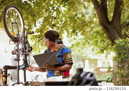 A healthy and lively african american fermale looking for bike gear maintenance for summer activities on internet. Sporty black woman searches for instructions on laptop to repair bicycle. A healthy and lively african american fermale looking for bike gear maintenance for summer activities on internet. Sporty black woman searches for instructions on laptop to repair bicycle. 116299110