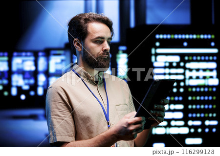 Qualified expert doing annual system review, checking data on tablet of needed server mendings. Clusters housing developed storage infrastructure supporting critical IT workloads 116299128