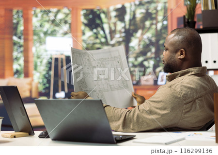 Professional entrepreneur evaluating building layout on blueprints, hunting property for leasing to relocate the office space. Investing in real estate for business development. 116299136