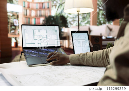 Businessman using digital tools to draft and plan office spaces to relocate, reviewing blueprints for a strategic and professional layout. Entrepreneur searching for new creative workspaces. 116299239