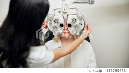 Optometrist, woman and phoropter for eye exam, vision and wellness in consultation room at hospital. People, doctor and patient with machine, lens and assessment for healthy eyesight in clinic Optometrist, woman and phoropter for eye exam, vision and wellness in consultation room at hospital. People, doctor and patient with machine, lens and assessment for healthy eyesight in clinic 116299458