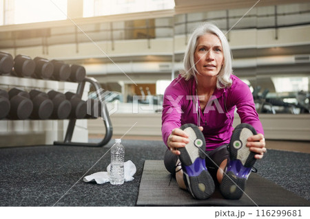 Mature woman, warm up and legs on gym floor, stretching and challenge for progress in workout. Person, muscle and start training for wellness with development, ready and exercise mat at fitness club 116299681