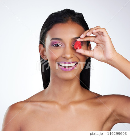 Raspberry, eye and woman in studio for skincare, nutrition and portrait on white background. Indian girl, fruit and smile with cosmetics for aesthetic, treatment and wellness or luxury and makeup 116299698