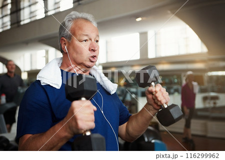 Mature man, weightlifting and exercise with dumbbells for fitness, workout or indoor training at gym. Male person with earphones for arm strength, muscle gain or listening to music at health club 116299962
