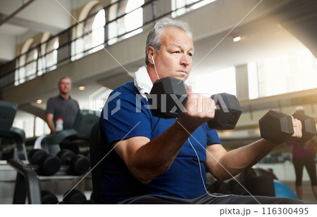 Mature man, earphones and weightlifting with dumbbells for workout, training or indoor exercise at gym. Male person with small weight for strength, muscle gain or power in fitness at health club 116300495