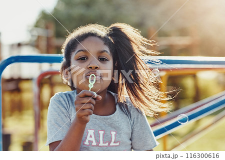 Portrait, girl and bubbles with playground, fun and love for summer break and play. Kid, roundabout and park equipment for joy, outside nature and happy child smile with countryside merry go round 116300616