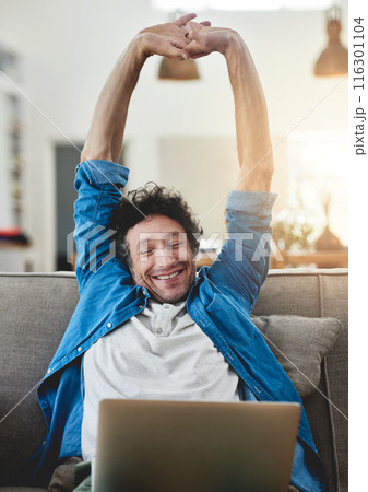 Stretching, relax and happy man on laptop in living room for freedom, finish or complete project in home. Peace of mind, computer and person on sofa for calm or freelancer resting on break in house 116301104