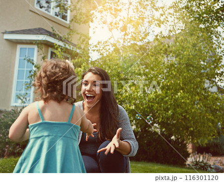 Mom, child and happy with bubbles in garden for games, excited or outdoor for bonding on grass at family house. Toddler, mother and daughter with soap, smile and love for connection on lawn in summer 116301120