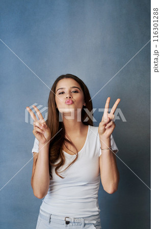 Peace sign, kiss and portrait of woman in studio for romance, affection and gratitude. Beauty, confidence and face of person with flirting emoji, positive hand gesture and love on blue background 116301288