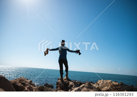 Woman photographer enjoy the view on sunrise seaside rocks 116301293