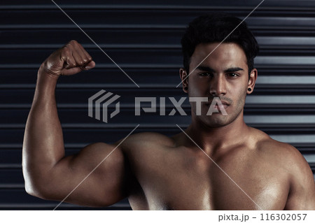 Flex, muscle and portrait of man with confidence, strong biceps and fitness goals in gym. Power, pride and serious male bodybuilder with body development, exercise and commitment to wellness 116302057