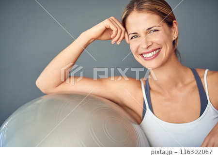 Woman, exercise ball and training for wellness, sitting and fitness with smile for motivation. Gym, health and athlete with wall background for workout planning, weight loss support and pilates 116302067