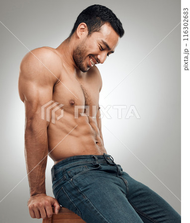 Man, chair and topless in studio for fitness, wellness and strong abs muscle on gray background. Male person, denim jeans and shirtless for health, bodybuilder and proud of body or workout results 116302683