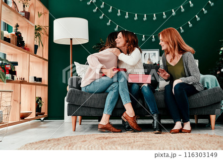 People, open presents and hug on Christmas for gift, celebration and box for festive season. Women, friends and embrace for package on December holiday, bonding and tradition of giving on xmas party 116303149