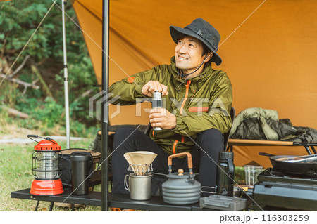 キャンプでコーヒーミルを使い豆を挽く男性キャンパー キャンプでコーヒーミルを使い豆を挽く男性キャンパー 116303259