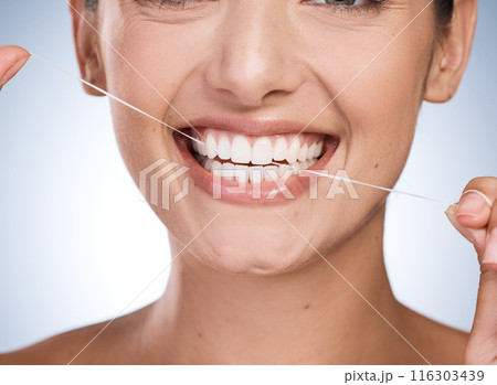 Woman, mouth and floss teeth in studio, orthodontics and cosmetics for smile on blue background. Female person, dental health and string for grooming, cleaning and self care or thread for plaque Woman, mouth and floss teeth in studio, orthodontics and cosmetics for smile on blue background. Female person, dental health and string for grooming, cleaning and self care or thread for plaque 116303439