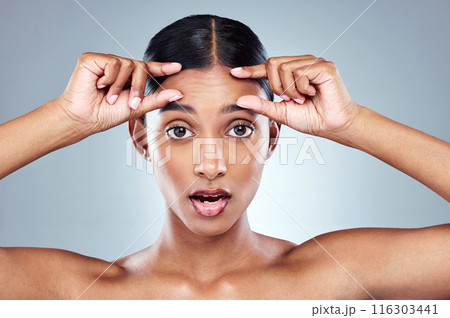 Portrait, woman and hands on forehead in studio for skin care, wellness and shock emoji. Eyes, filler and surprise for dermatology by grey background with cosmetics, collagen and detox with facial 116303441