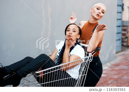 Friends, portrait and shopping cart for blowing kiss, outdoor and bonding together in city for love. Women, town and adventure in trolley for support, emoji and flirting gesture in urban on weekend 116303561
