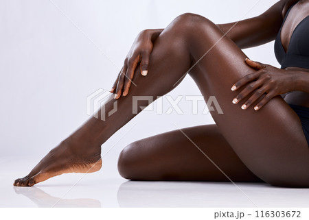 Black person, legs and skincare in studio for hair removal, epilation and smooth skin on white background. Body, woman and hands touching with manicure for wellness, waxing or moisturize and beauty 116303672