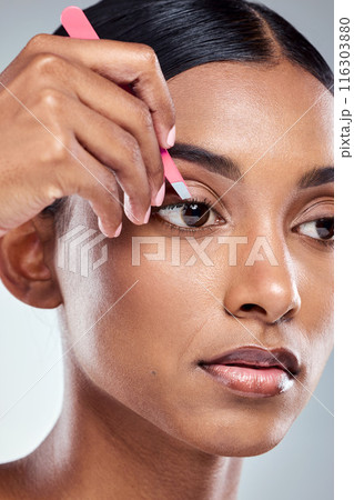 Face, tweezer and woman in studio for hair removal, correction and skincare on gray background. Indian girl, plucking and hand by eye for self care, beauty and epilation or dermatology with tool 116303880
