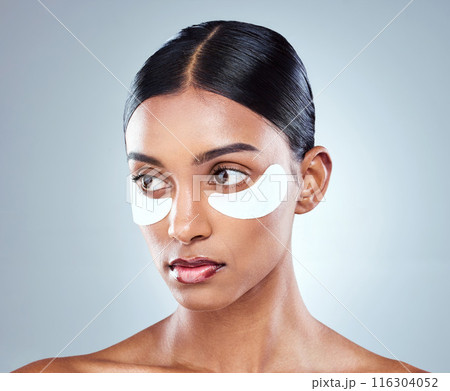 Indian woman, face and eye patch for beauty and skincare, hydration and refresh on white background. Thinking, dermatology and facial treatment for collagen, detox and serious female person in studio 116304052